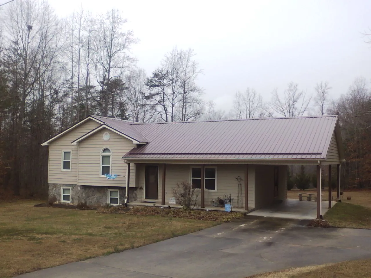 Burgundy metal roof on a tan split level home with an attached carport in Englewood Cliffs