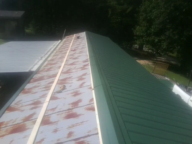 Old rusted panels beside newly installed green metal roofing — Wind Damage Roof Repair by Roofing Brothers in Englewood Cliffs