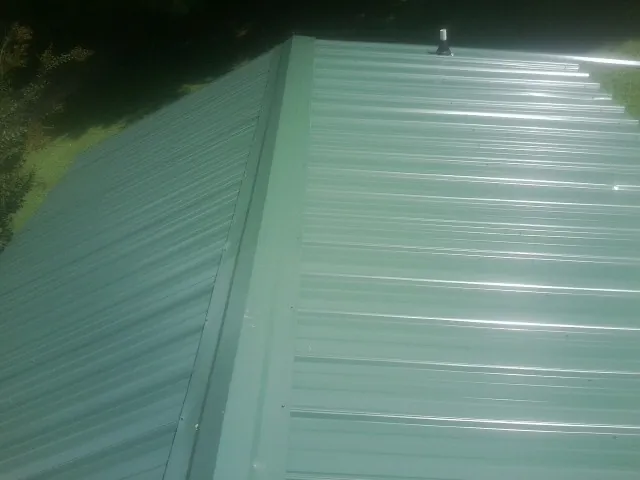 New green metal panels meeting at the ridge of a roof — Flat Roof Repair work by our crew in Englewood Cliffs