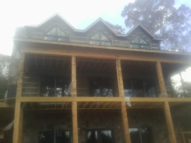 Dormers and porch framing on a large log home under construction — Roof Coating work by our crew in Englewood Cliffs