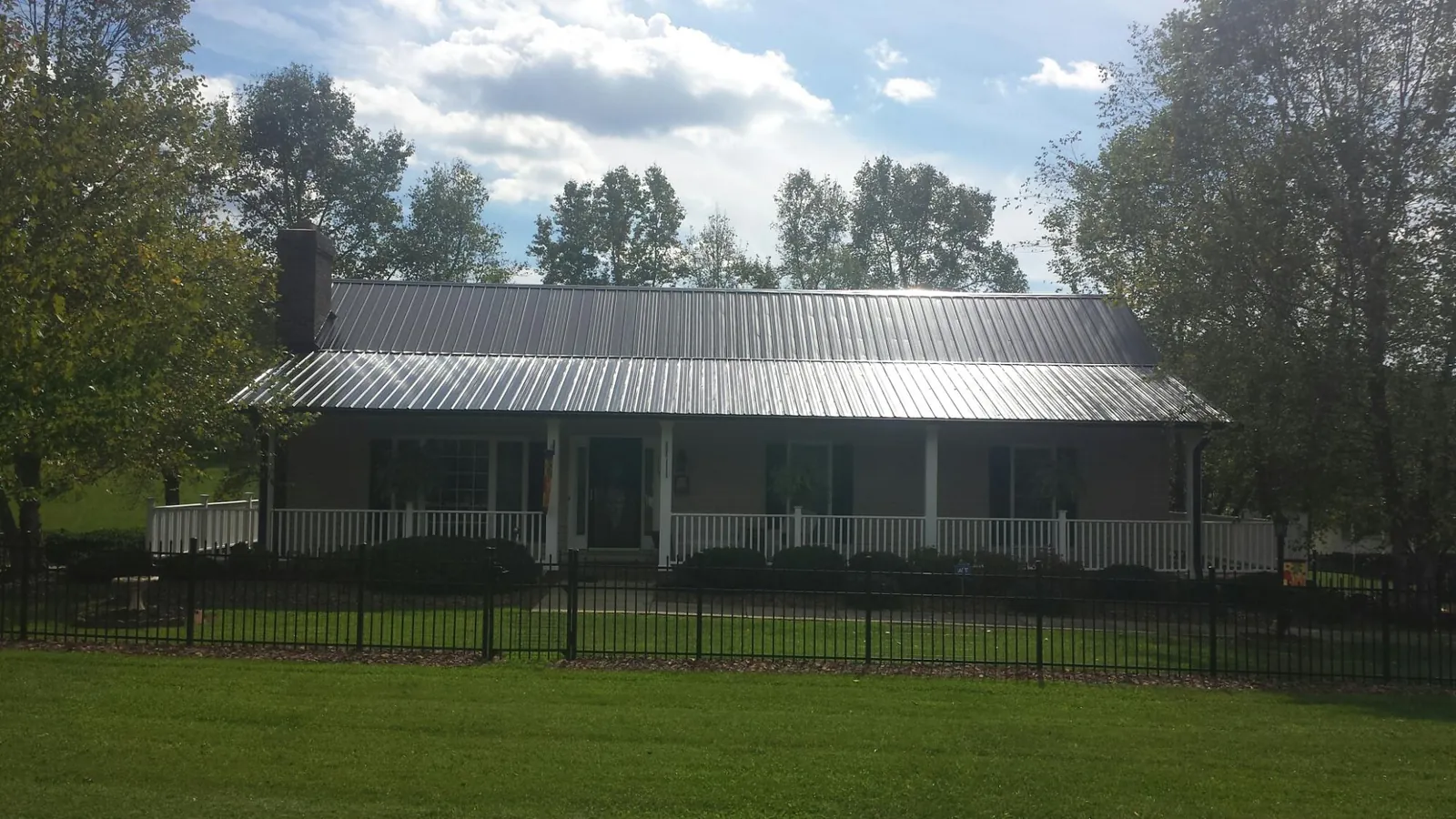 Gray metal roof on a brick ranch with a full width front porch — Gutter Guard Installation work by our crew in Englewood Cliffs