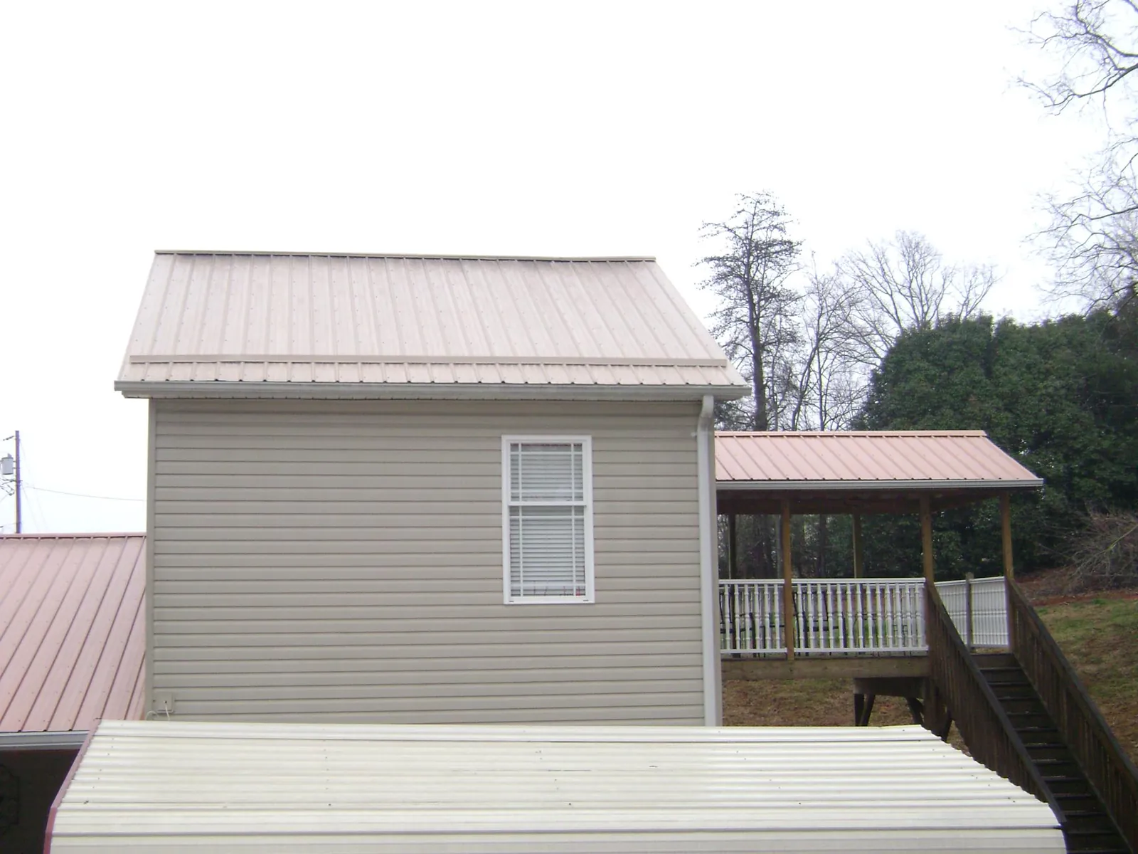 Tan metal roofs on a two story addition and attached porch, from a Roof Replacement job in Englewood Cliffs