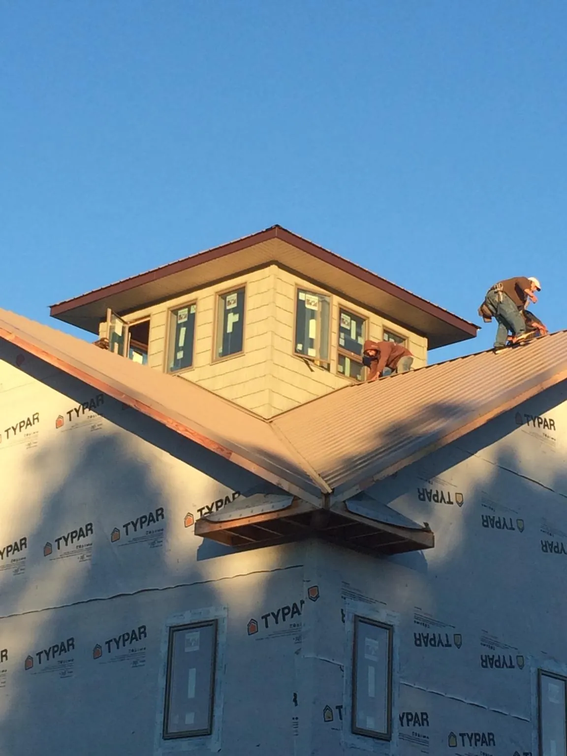 Roofers working around a rooftop cupola on a new metal roof at sunset — Roof Waterproofing in Englewood Cliffs by Roofing Brothers